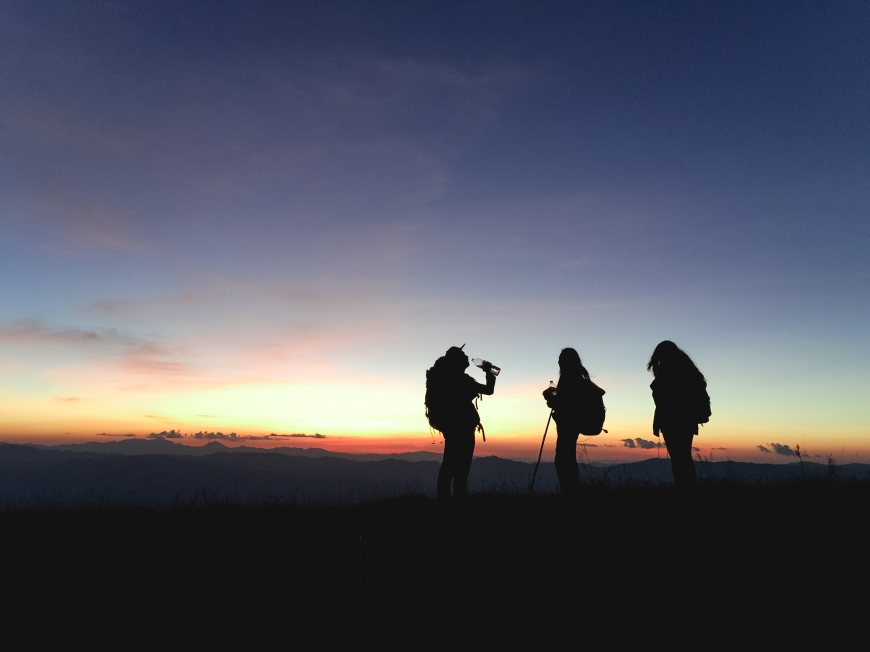 Silhouettes of group hikers people with backpacks enjoying sunse